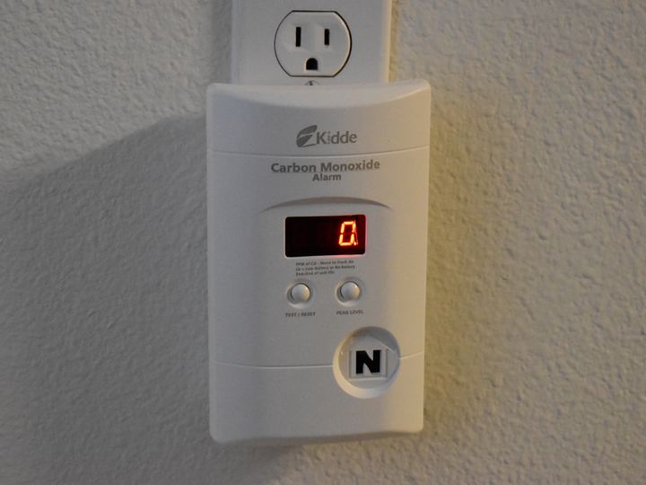 A plug-in carbon monoxide alarm with a digital display on a wall outlet