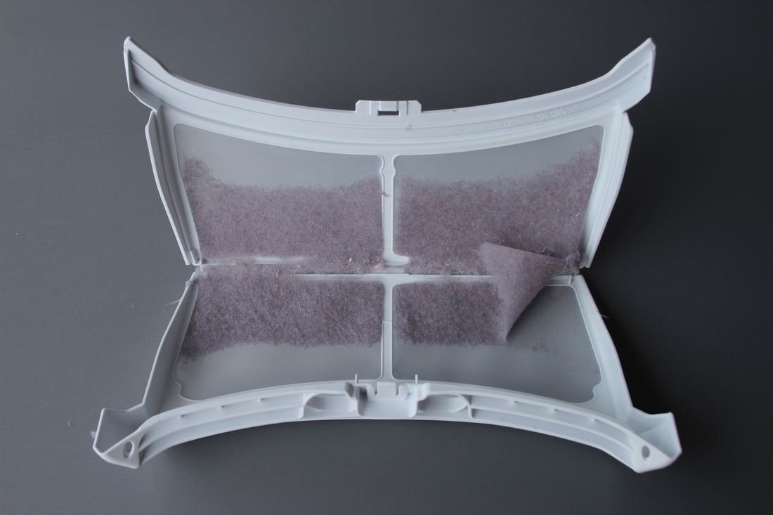 An opened dryer lint filter holding a layer of lint