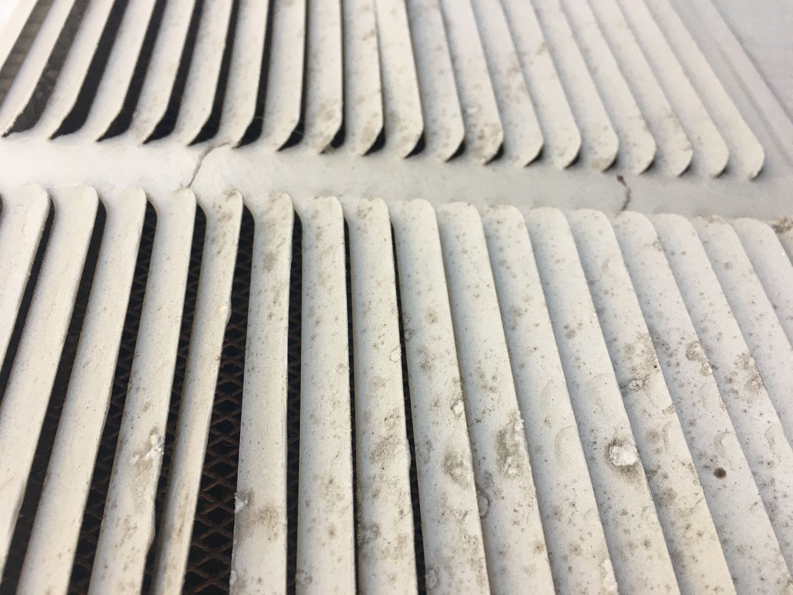 Close-up of a dusty air vent with grey dust on its louvers