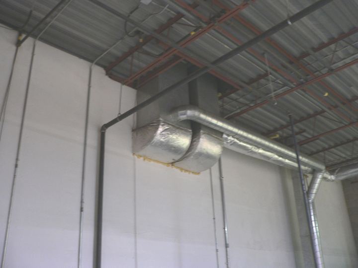 Metal and foil wrapped ducts running along a wall and ceiling