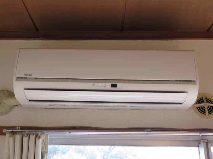 A white wall-mounted ductless air conditioner indoor unit above a window
