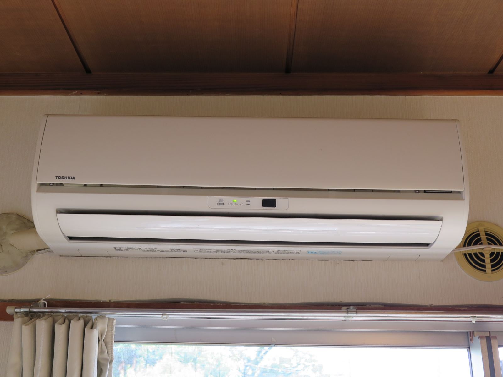 A white wall-mounted ductless air conditioner indoor unit above a window