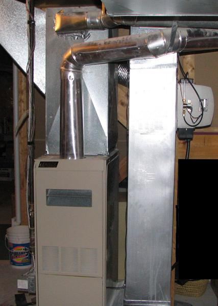A residential gas furnace in a basement with metal ductwork above it