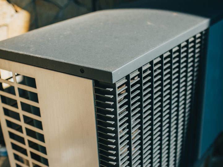 An outdoor air conditioner unit beside a house wall in a garden