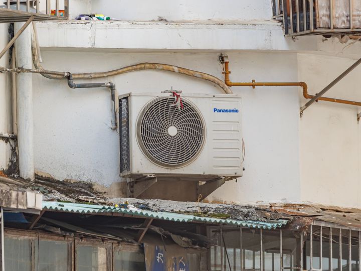 An outdoor air conditioner condenser unit beside a building