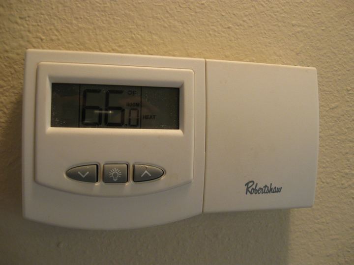 A digital wall thermostat showing 66 degrees
