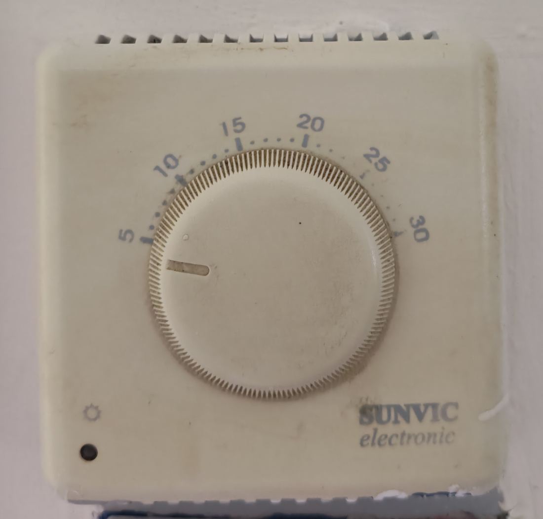 An older dial thermostat with a temperature scale