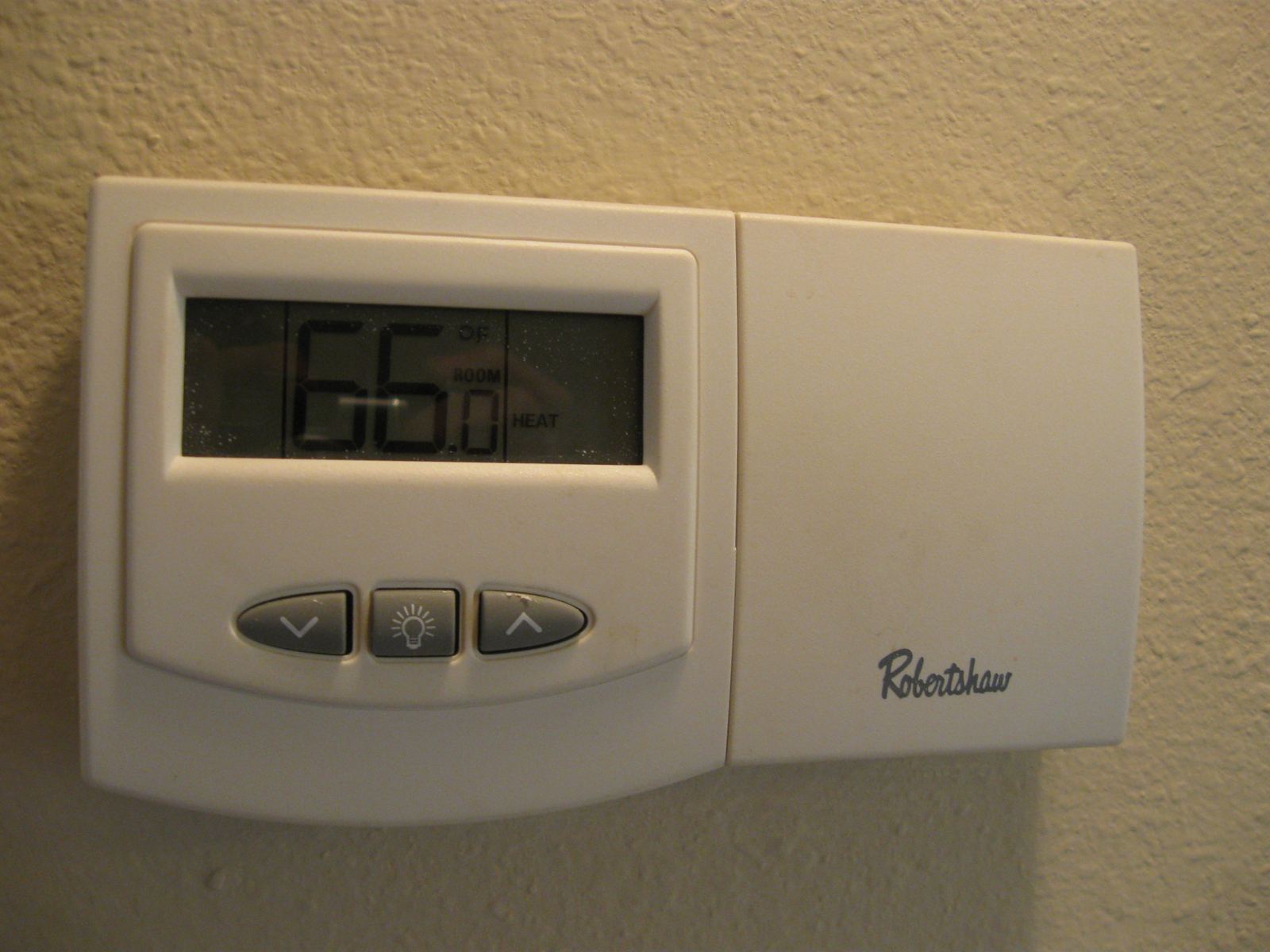 A digital wall thermostat showing 66 degrees