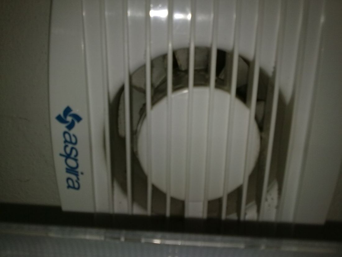 A bathroom exhaust fan grille on a wall