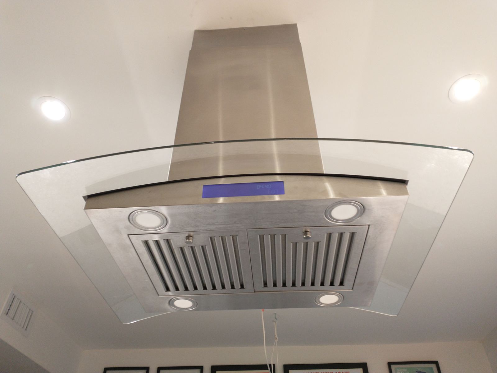 A stainless steel and glass range hood above a kitchen cooktop